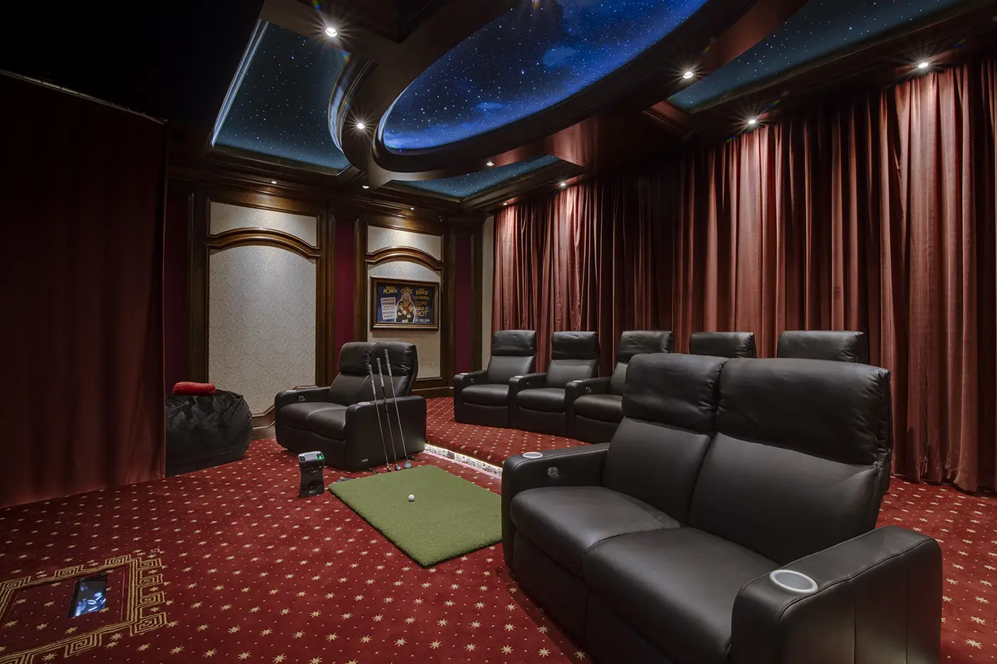 Elegant home theater with a golf simulator setup, featuring CinemaTech's luxurious Valentino seating. This room combines the immersive ambiance of star ceilings with the practicality of a golf simulator area, creating a dual-purpose space that’s perfect for entertainment and relaxation. Discover inspiring golf simulator room ideas, designed with attention to detail and optimized for sound and style, ideal for those seeking the best in golf simulator room dimensions and luxury home theater design.